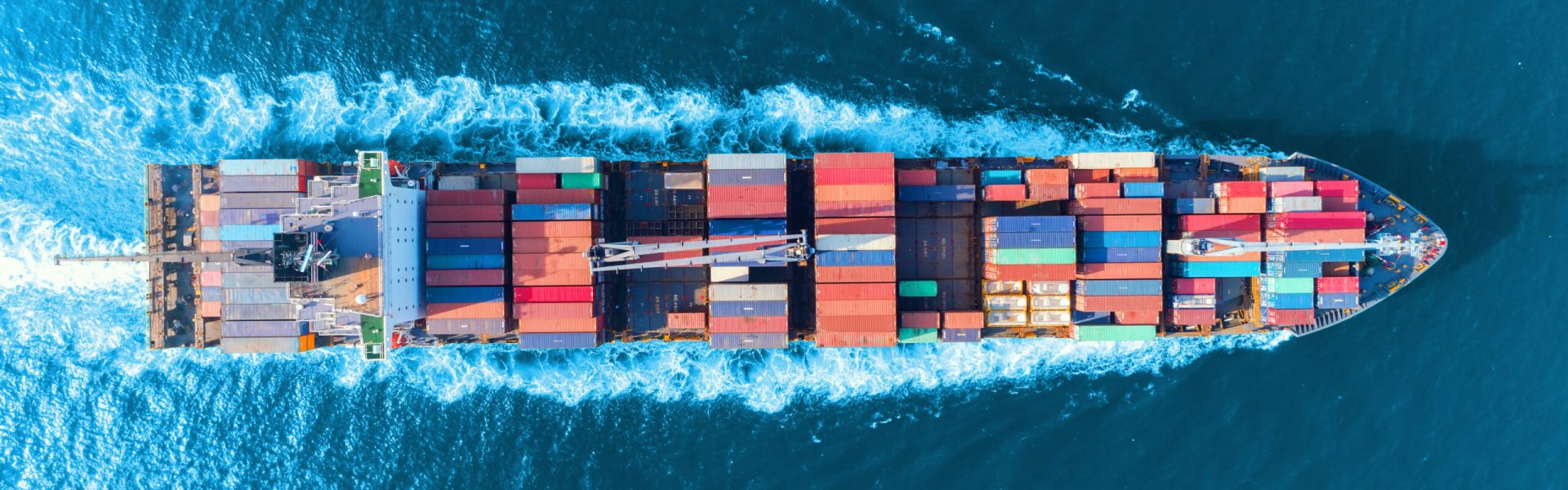 Aerial top view full speed container ship in the sea for logistics import export, shipping or transportation concept.